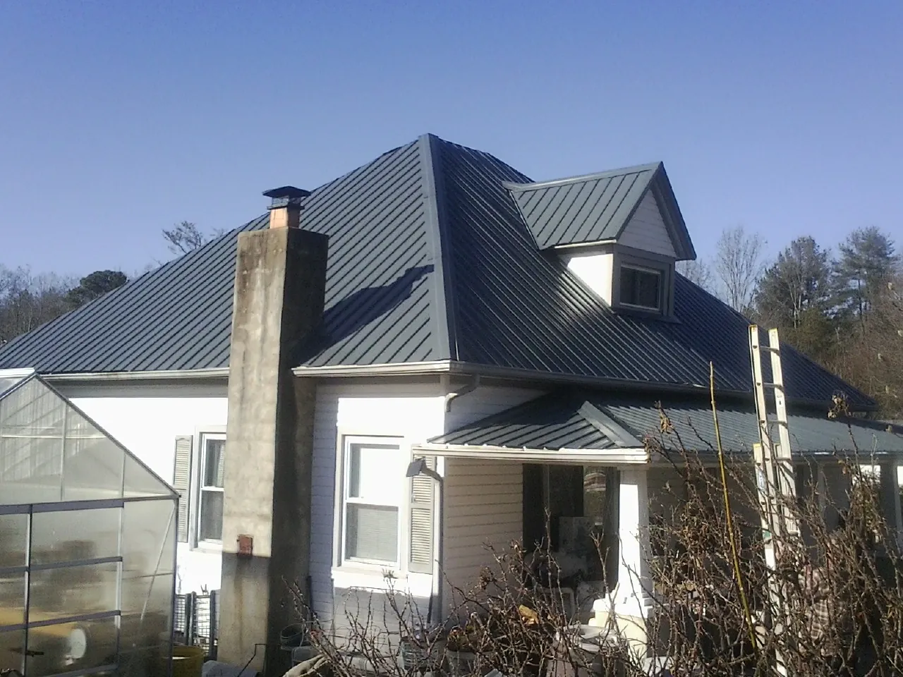 Dark blue standing seam metal roof on a white farmhouse with dormer — Slate & Tile Roof Repair by Roofing Brothers in San Leandro