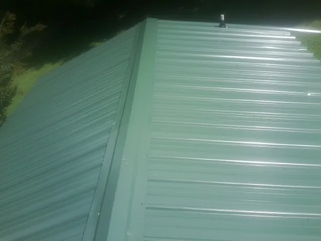 New green metal panels meeting at the ridge of a roof — Flat Roof Repair work by our crew in San Leandro