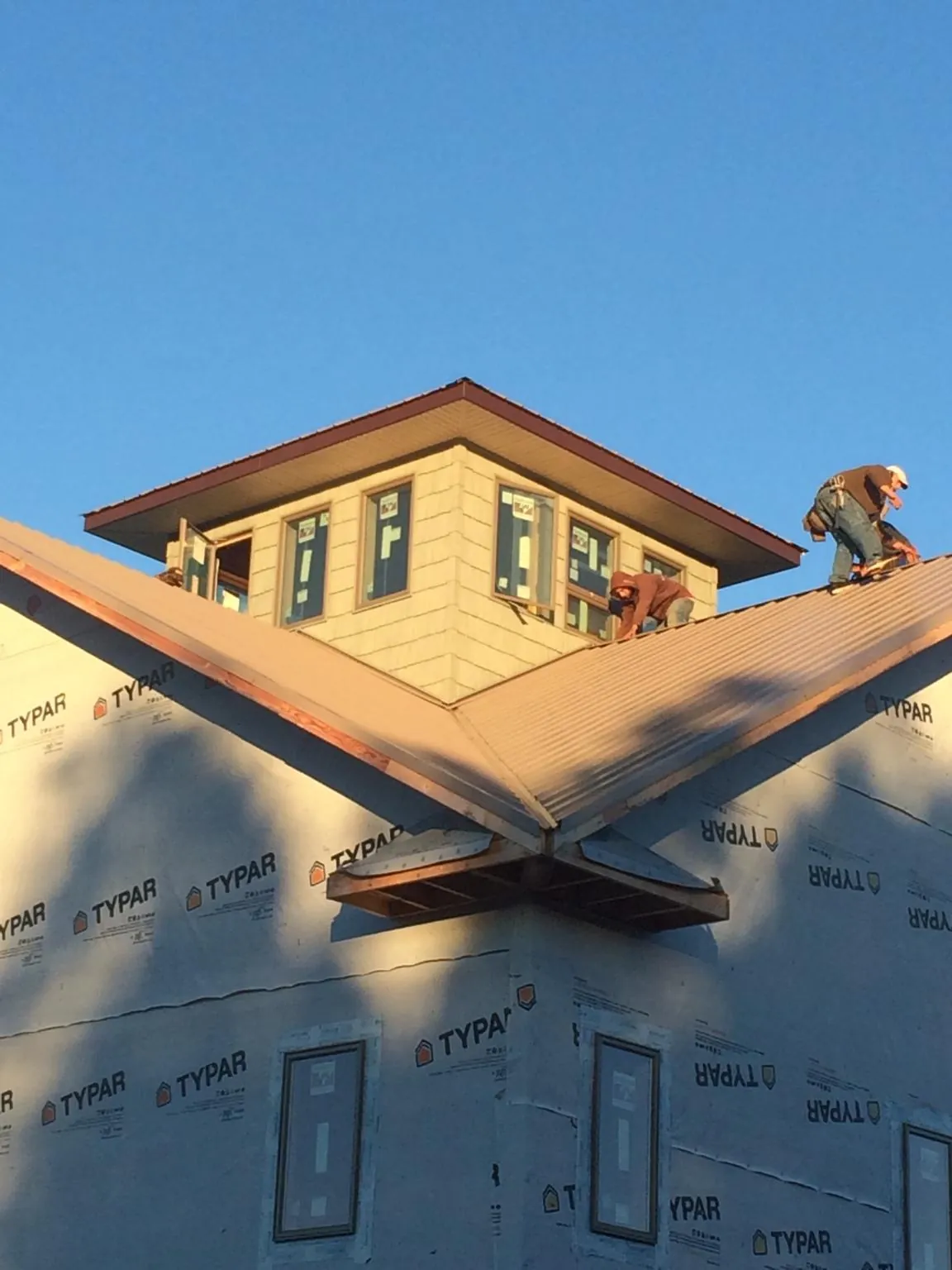 Roofers working around a rooftop cupola on a new metal roof at sunset — Roof Waterproofing in San Leandro by Roofing Brothers